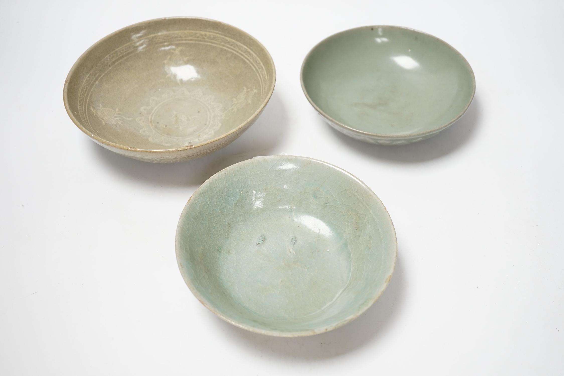 Two Korean celadon bowls, Goryeo dynasty (11th/12th century), the first carved with lotus petals to the underside, the second with fine crackle to the glaze, and a Korean slip-decorated celadon bowl (11th/12th century),